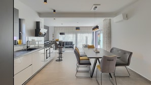 A modern kitchen with a dining area, featuring a central island, bar stools, and pendant lighting. - Amazing home in Porec (Porec)