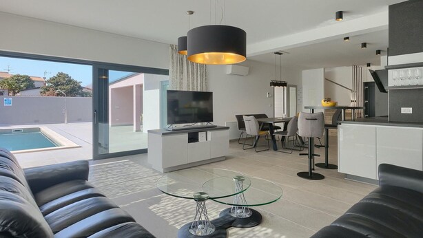 A modern living room with a TV, sofa, glass coffee table, and a dining area with chairs and a table. - Amazing home in Porec (Porec)