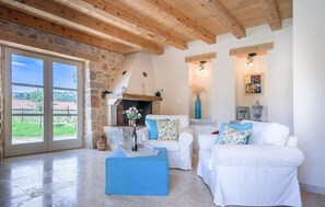 Relax in this inviting living room with a stone fireplace, large windows, and a comfortable sofa set.