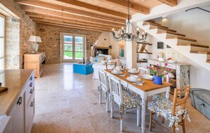 Enjoy meals in this dining area with a long table, chandelier, and large window.