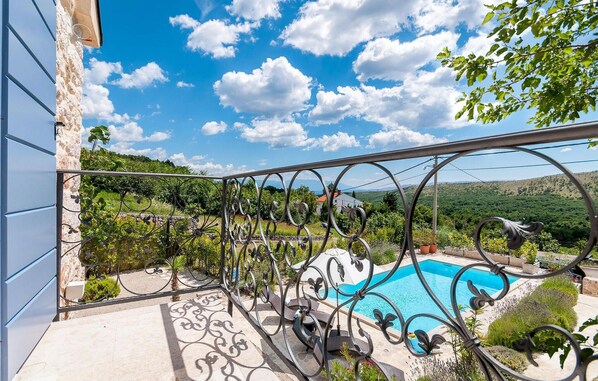 Enjoy the serene views of the pool and surrounding landscape from this balcony.