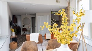 A dining area with a white vase of yellow flowers on a table, surrounded by wooden chairs. - Duplex 2 Bedroom and 1.5 Bath Retreat Near Loyola Park (Chicago)