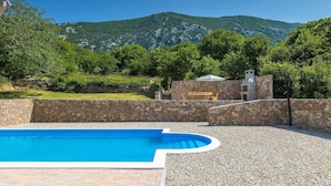 A swimming pool with a stone wall and a stone building with a chimney in the background. - Amazing home in Drivenik (Drivenik)