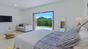 A bedroom with a large bed, a sofa, a TV, and a view of a forest and castle. - Cozy home in Drivenik (Drivenik)