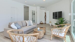 A modern living room with a sofa, wicker chairs, a coffee table, and a TV. - Cozy home in Drivenik (Drivenik)