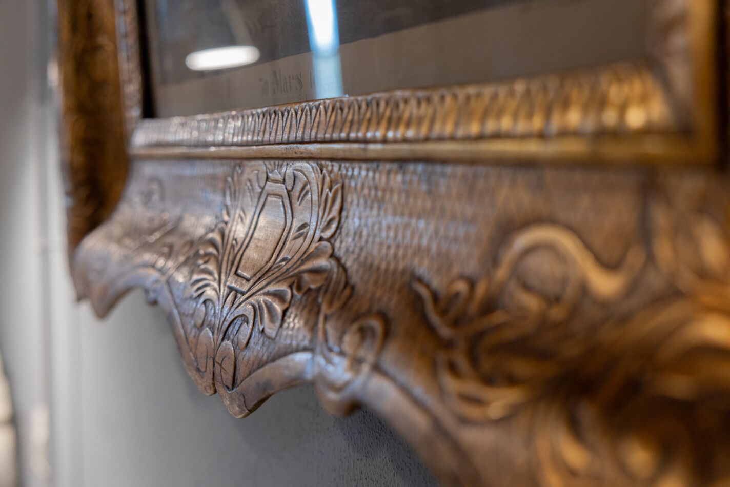 A close-up of an ornate, gold-colored frame with intricate carvings.