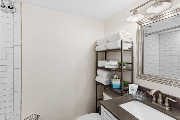 A bathroom with a white sink, a mirror, and a towel rack with neatly folded towels. - SALTY PELICAN (Galveston)