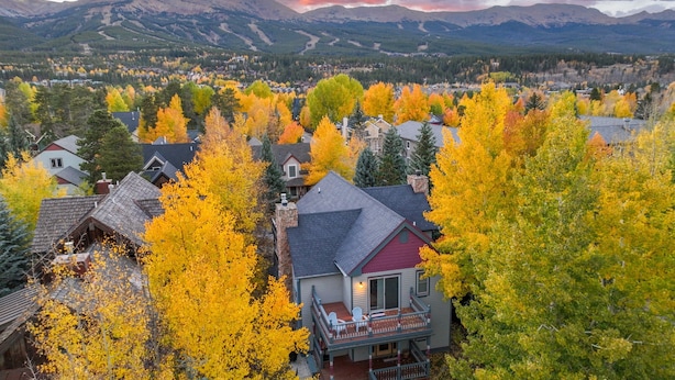 A residential area with houses surrounded by autumn foliage, a prominent house with a balcony, and mountains in the background. - Downtown, Walk to Main, 1 mile to ski resort (Breckenridge)