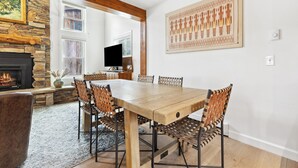 A dining area with a wooden table and woven chairs, a stone fireplace, and a large wall art piece. - Downtown, Walk to Main, 1 mile to ski resort (Breckenridge)