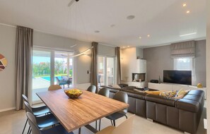 Una sala de estar moderna con una mesa de comedor de madera, un sofá y un televisor.