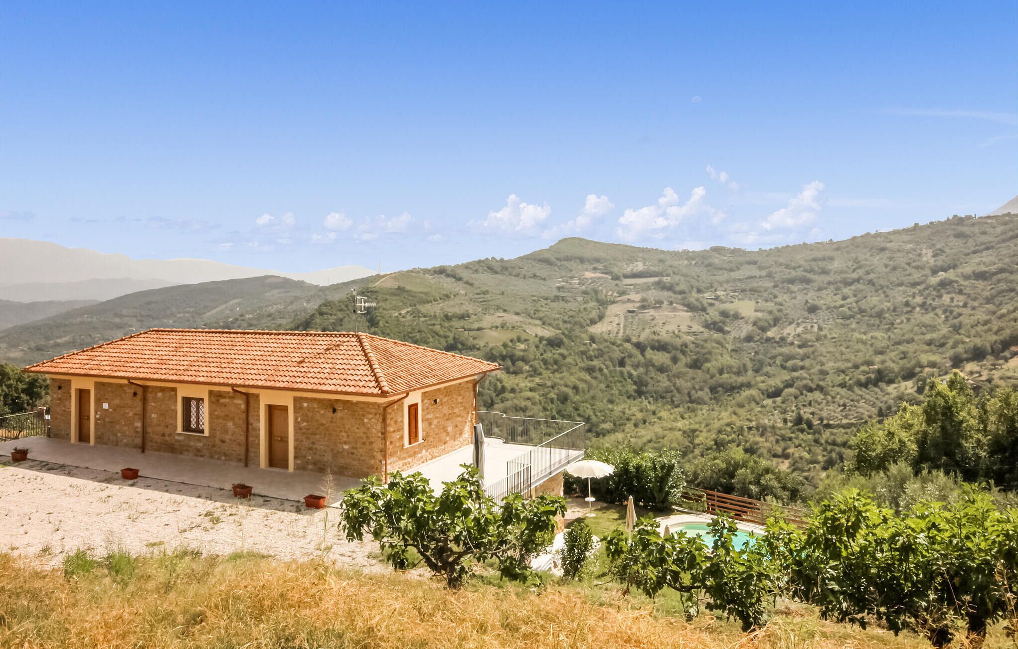 A single-story building with a tiled roof, a patio area, and a pool.