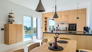 Una cocina moderna con armarios de madera, una isla central y una zona de comedor con una mesa y sillas.