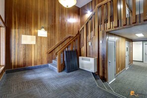 A spacious lobby with a wooden staircase, a reception desk, and a modern air conditioning unit. - Alyeska Slope-Side Sanctuary Ski-In Ski-Out (Girdwood)