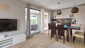 Eine moderne Wohnung mit Essbereich, Küche und einem Balkon mit Vorhängen.