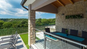 Ein Balkon mit Steinmauer, Glasgeländer und Pool.