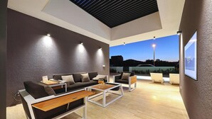 A modern living room with a sofa, coffee table, and chairs, a large window with a view of the outside, and a ceiling with a skylight. - Beach front home in Kraj (Kraj)