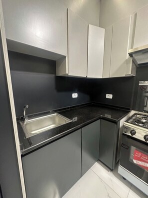 Une cuisine équipée d’un évier à deux bacs, d’une cuisinière et de placards.