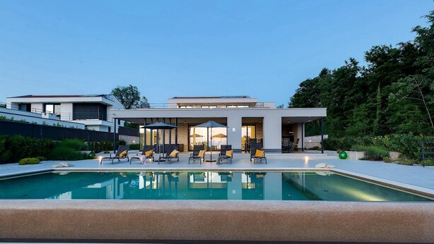 Een modern huis met een zwembad, buiten zitplaatsen en een overdekt terras.