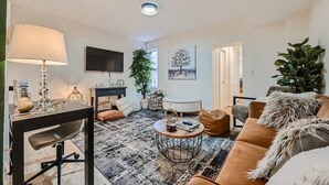 A modern living room with a sofa, coffee table, and a TV mounted on the wall. - Baltimore Beauty! Johns Hopkins! Private Parking! (Baltimore)