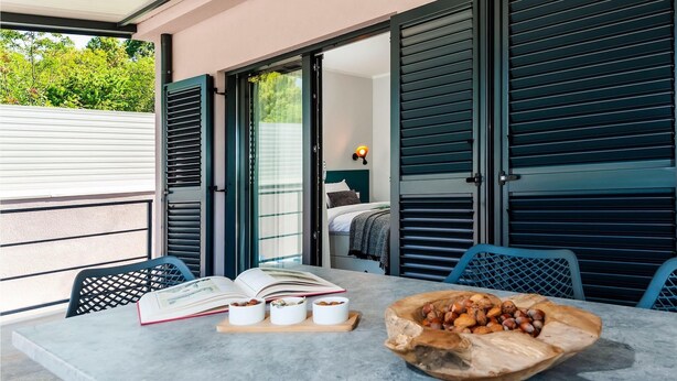 A modern outdoor seating area with a table, chairs, and a wooden bowl of nuts.