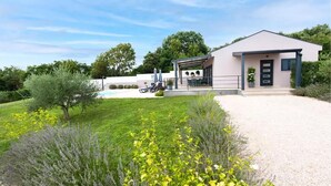 A modern building with a covered patio area, a swimming pool, and a well-maintained garden with various plants.