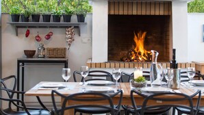An outdoor dining area with a fireplace, potted plants, and a table set for two. - Gorgeous home in Kastel Stafilic (Kastel Stafilic)