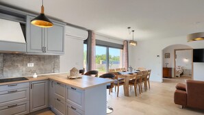 Eine moderne Küche mit grauen Schränken, einer Holztheke und Pendelleuchten.