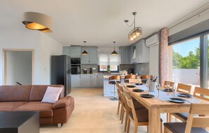 A modern kitchen with grey cabinets, a central island, and pendant lighting.