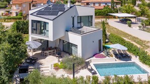 A modern two-story house with a rooftop solar panel array, a swimming pool, and a patio with outdoor furniture. - Pet friendly home in Porec (Porec)