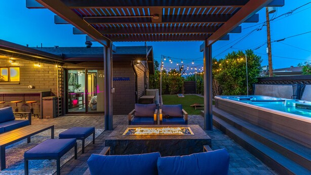 Eine Außenpatio mit Whirlpool, Sitzbereich und überdachtem Bereich mit Ziegelwand und Neonreklame.