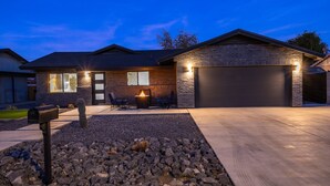 Ein modernes Haus mit Garage, Feuerstelle und einer gut beleuchteten Auffahrt.
