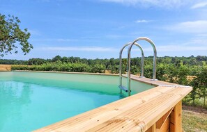 Relax by the serene pool surrounded by lush greenery and trees.