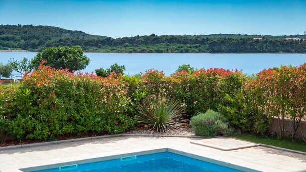 Una piscina con vistas a un lago y colinas al fondo.