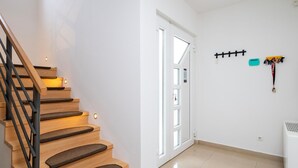 Portaat, joissa on puiset askelmat ja mustat kaiteet, johtavat valkoiseen oveen, jossa on lasiruudut.