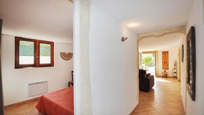 A room with a bed, a radiator, a window, and a door leading to another room.