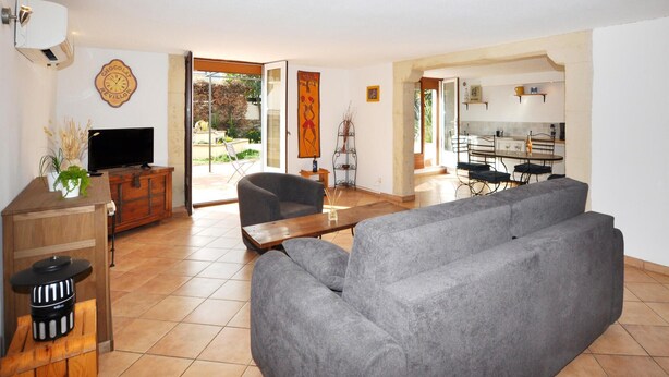 A living room with a grey sofa, a wooden coffee table, a TV on a wooden cabinet, and a sliding glass door leading to a patio.