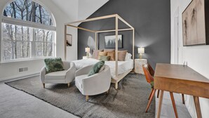 A modern bedroom with a four-poster bed, a large window, and a dining area. - Poconos Luxury Retreat - Hot-Tub, Billiards, Game Room, Fire-Pit, Private! (Tobyhanna)
