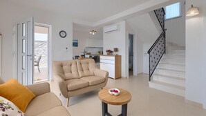 Ein modernes Wohnzimmer mit einem beigen Sofa, einem kleinen runden Holztisch mit einer Schüssel und einer Treppe mit schwarzer Geländer.