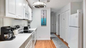 A modern kitchen with white cabinets, a coffee maker, and a ceiling fan. - Ocean Walk Condo Upstairs Unit (St. Simons Island)