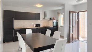 Una cocina moderna con armarios oscuros, una isla central y sillas blancas.