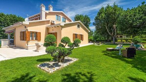 A two-story house with a well-maintained lawn and a small garden area with a tree and a fountain. - Nice home in Labin - Rabac (Labin - Rabac)