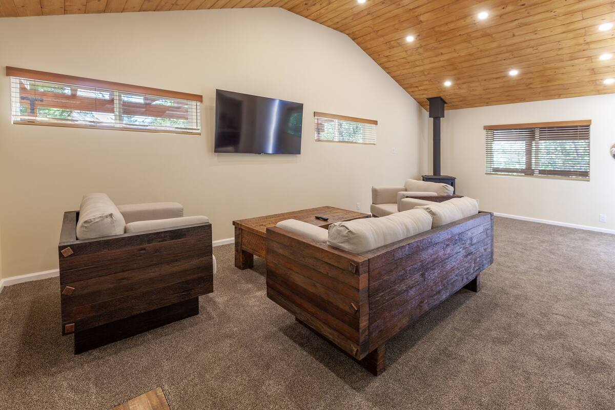 A cozy living room with a wooden bench, a sofa, and a flat-screen TV on the wall.