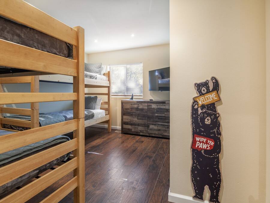 A room with bunk beds, a dresser, and a bear decoration on the door.