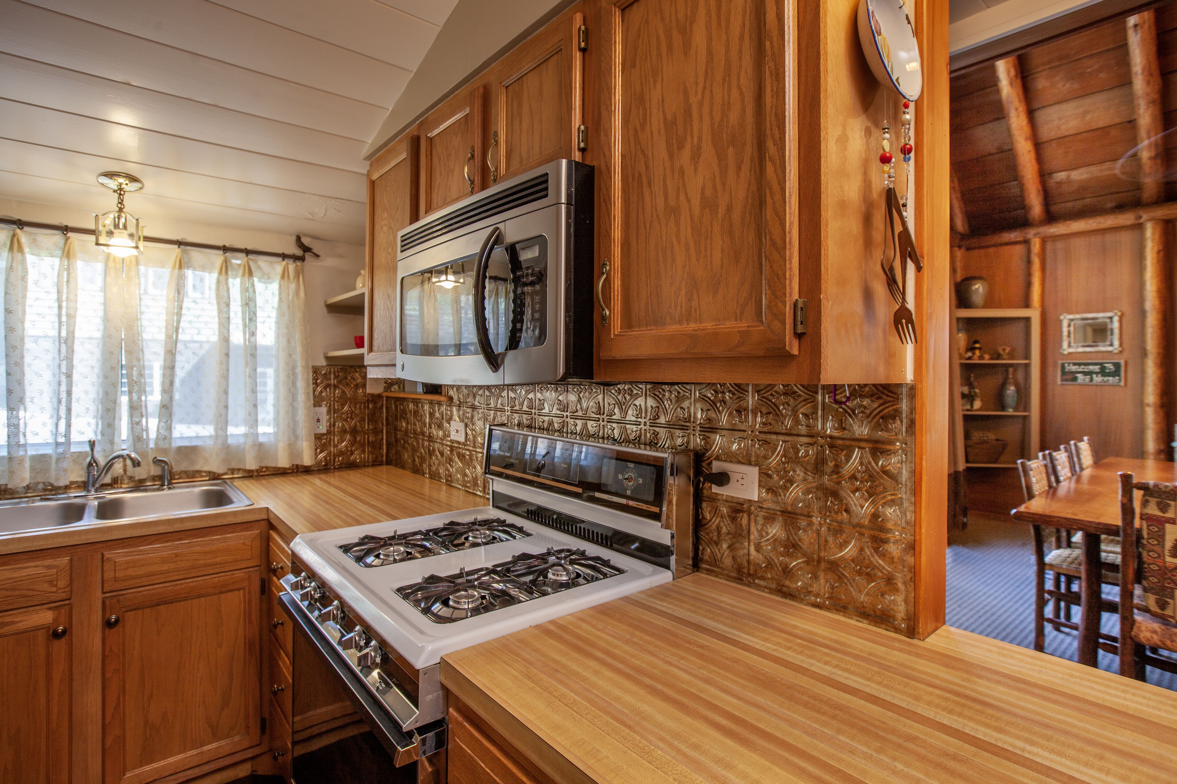 A kitchen with wooden cabinets, a stove, a microwave, and a sink.