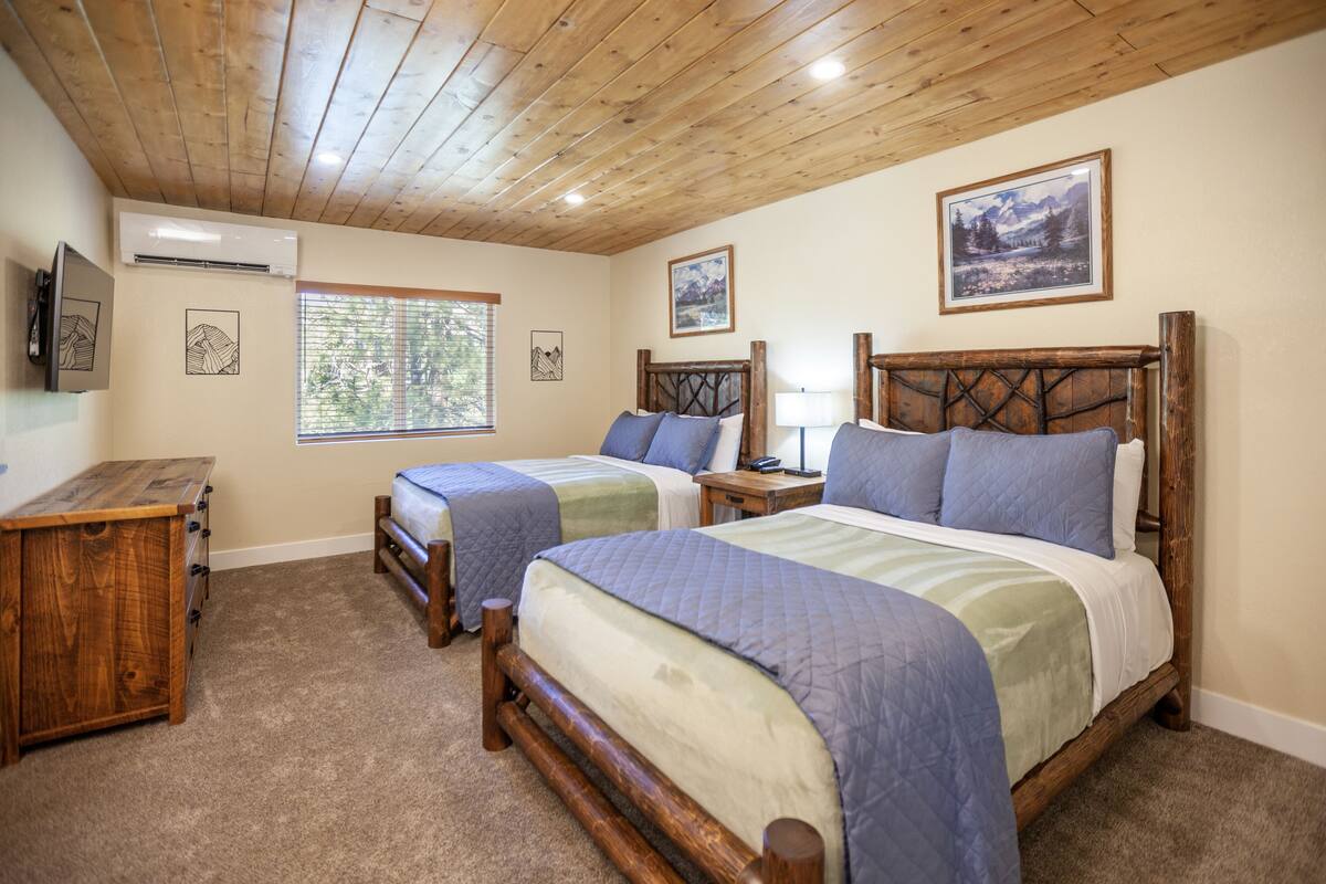 A bedroom with two beds, wooden headboards, and a wooden dresser.