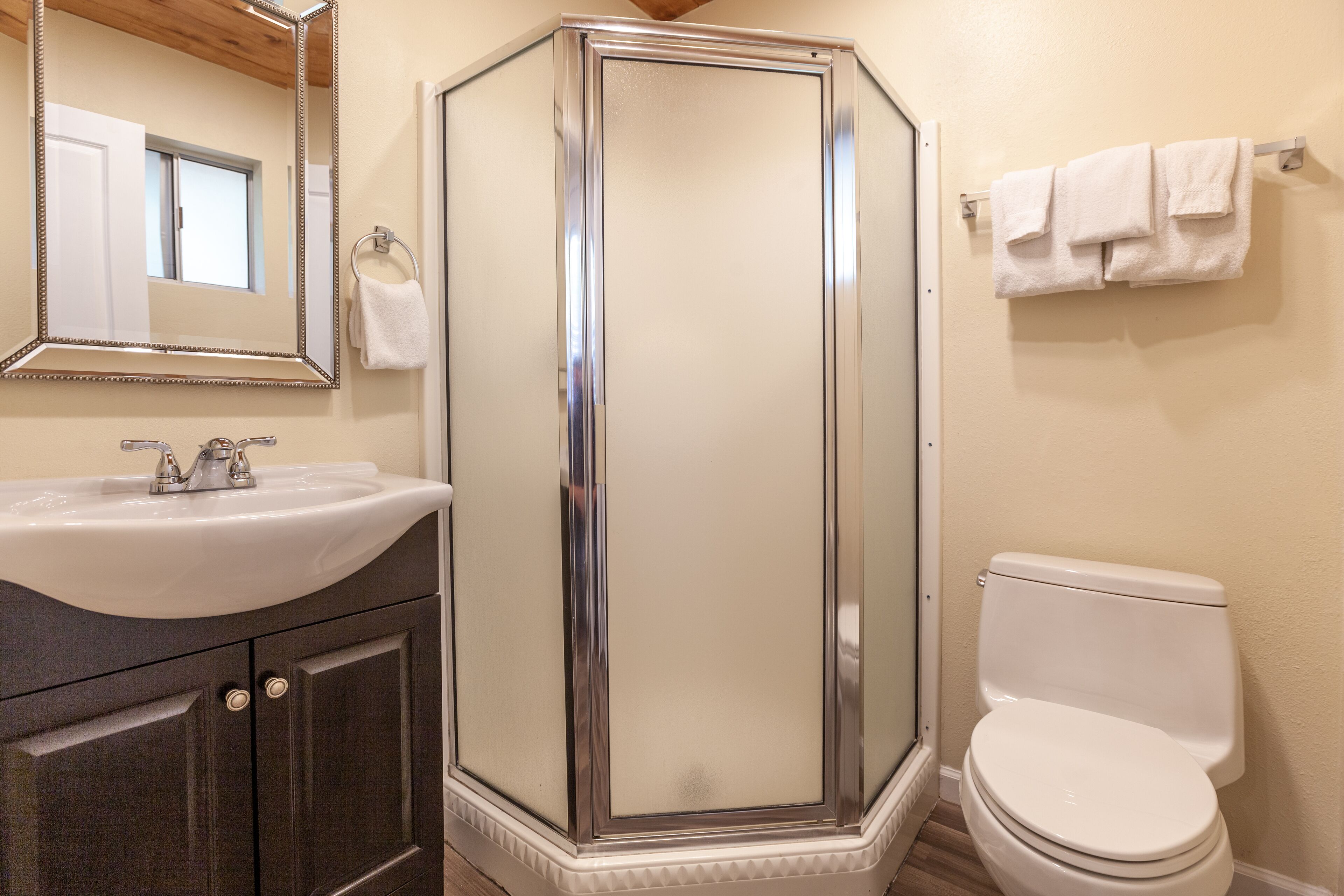 Un baño con cabina de ducha, lavamanos e inodoro.