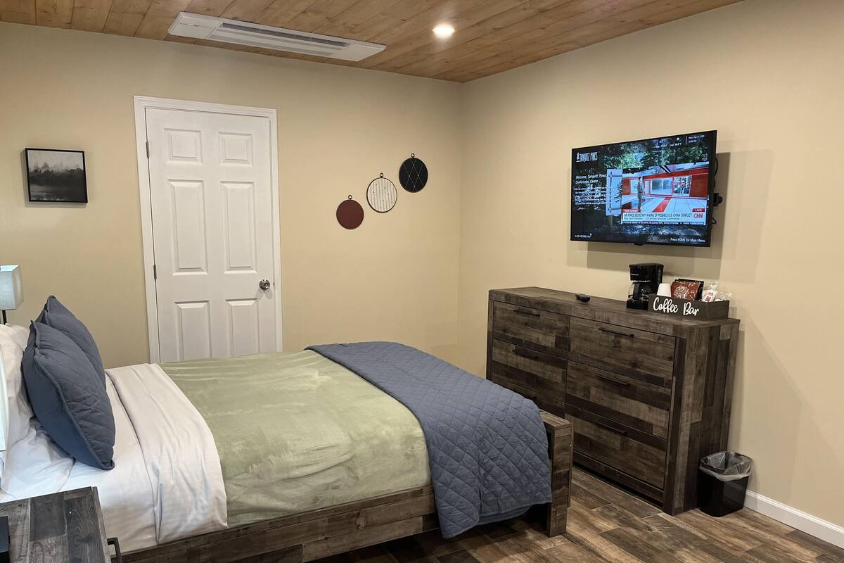 A bedroom with a bed, a dresser, a TV, and a door.