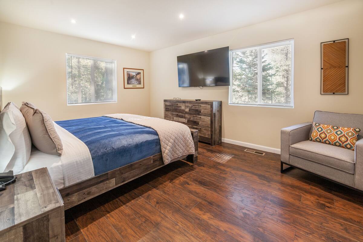 A bedroom with a bed, a dresser, a TV, and a sofa.