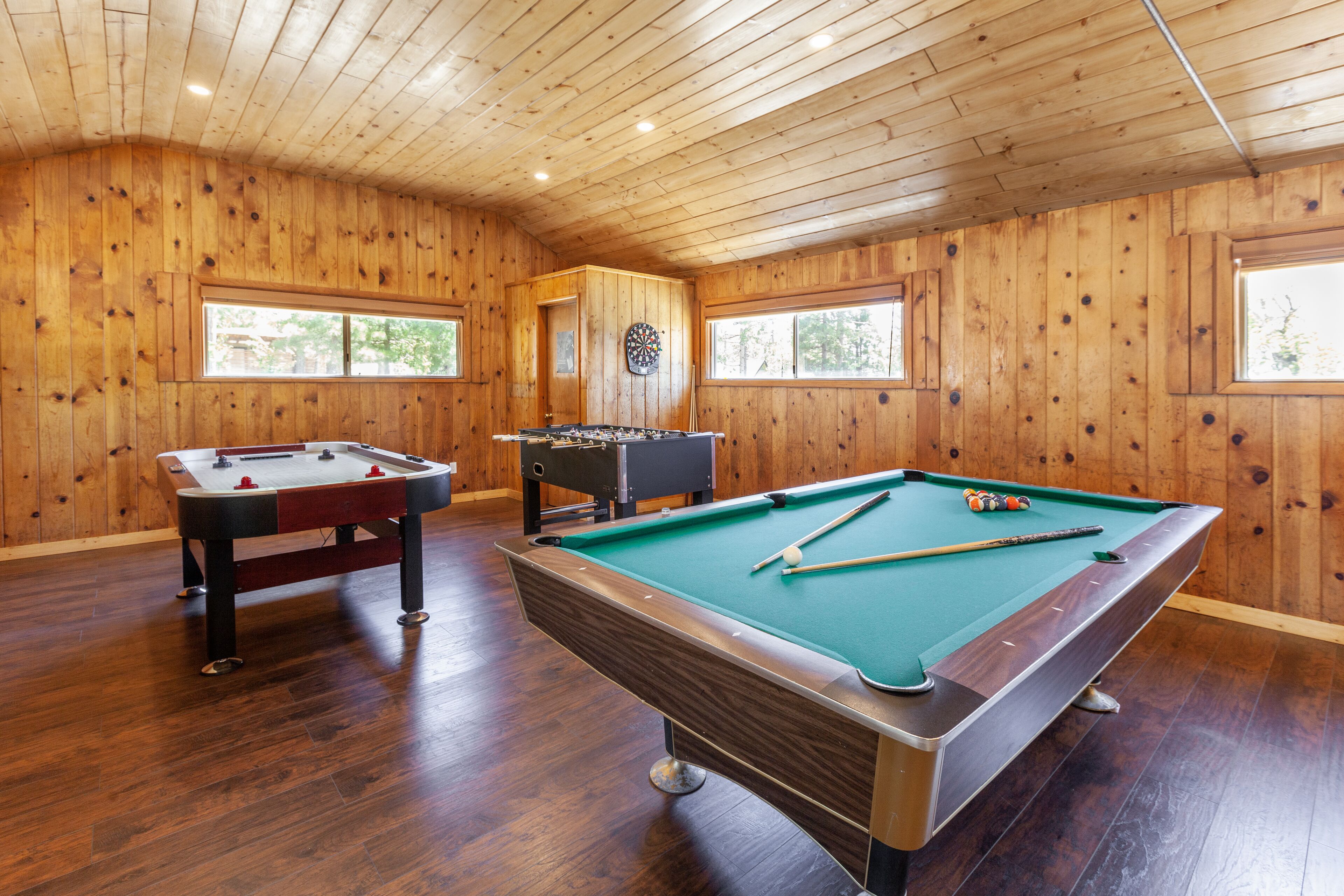 Une pièce aux murs lambrissés, équipée d’une table de billard, d’un baby-foot et d’un jeu de fléchettes.