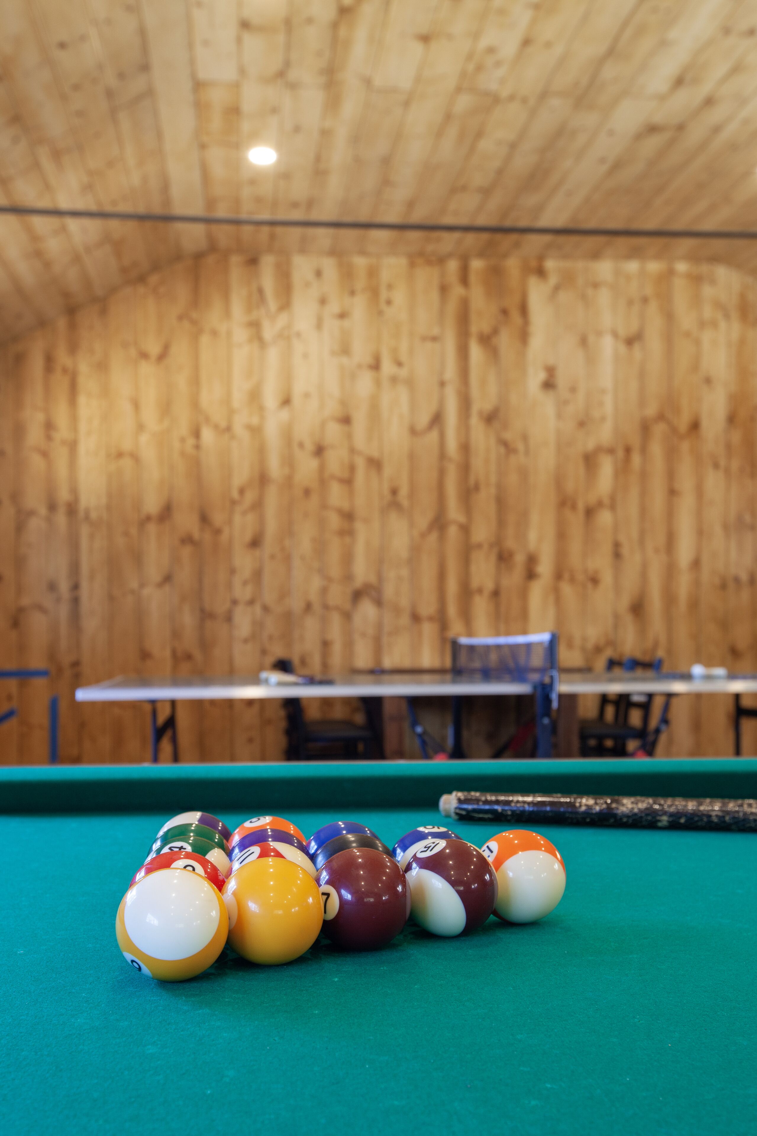 A pool table with billiard balls and a wooden ceiling.